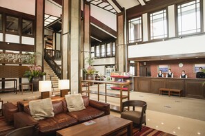 A spacious lobby with a leather sofa, a wooden reception desk, and a staircase. - HOLE37 (Tsukuba)