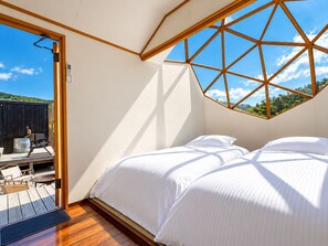 Een slaapkamer met een houten balken plafond, een bed en uitzicht op de omgeving.