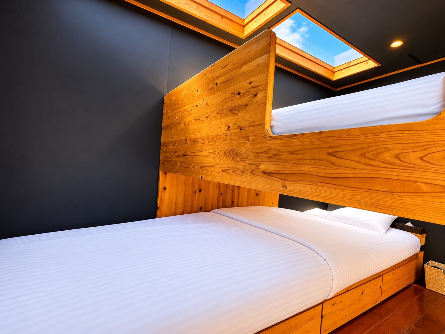 A bunk bed with a wooden headboard and a skylight above.