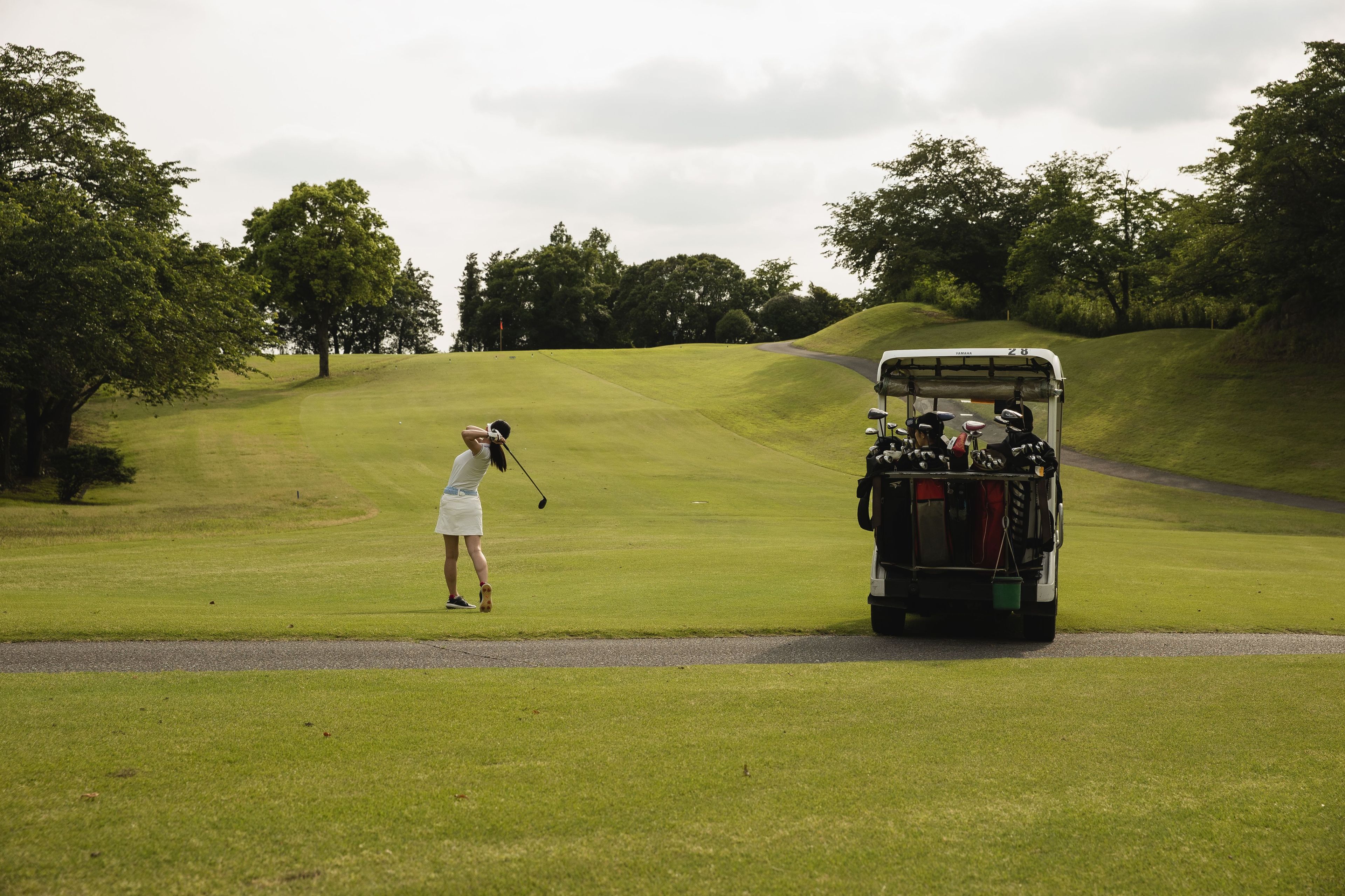 A golf course with a cart and a golfer.