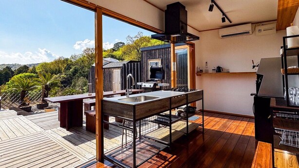 A modern kitchen with a large window, wooden deck, and a view of the surrounding landscape. - HOLE37 (Tsukuba)