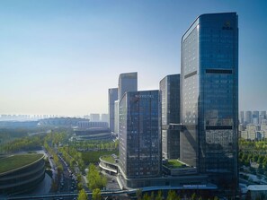 A modern hotel with a curved glass facade, a prominent 'NOVOTEL' sign, and a view of the surrounding urban landscape.