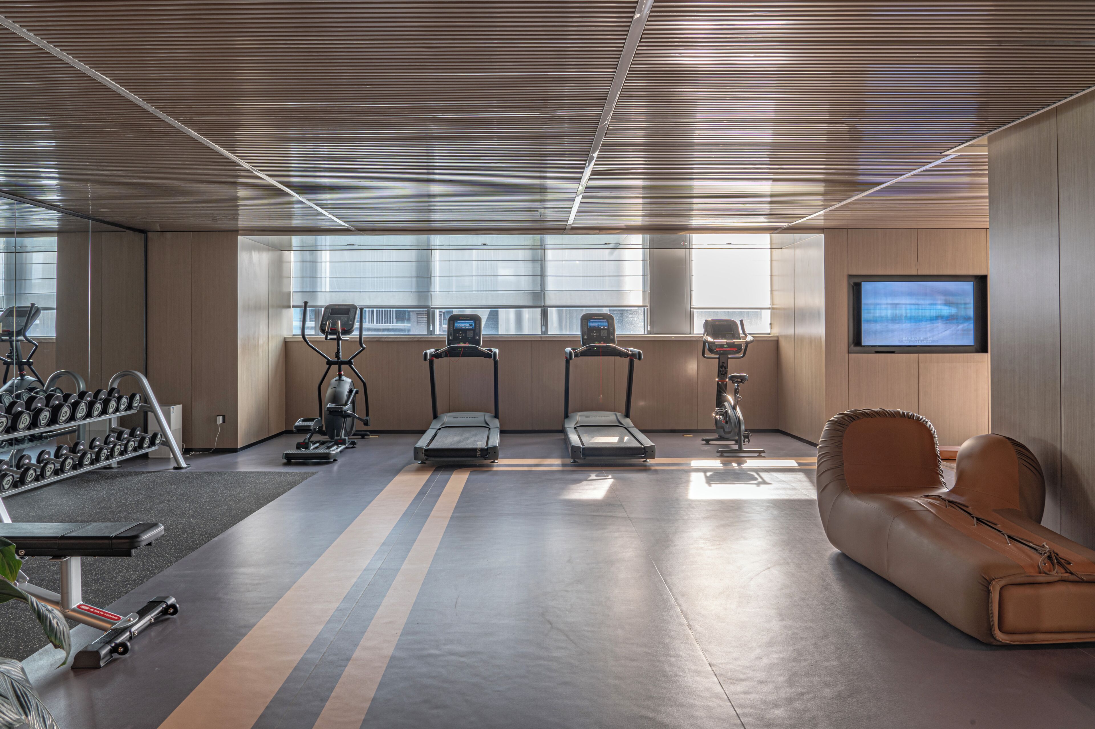 Una palestra con tapis roulant, macchinari ellittici e rastrelliere per pesi.