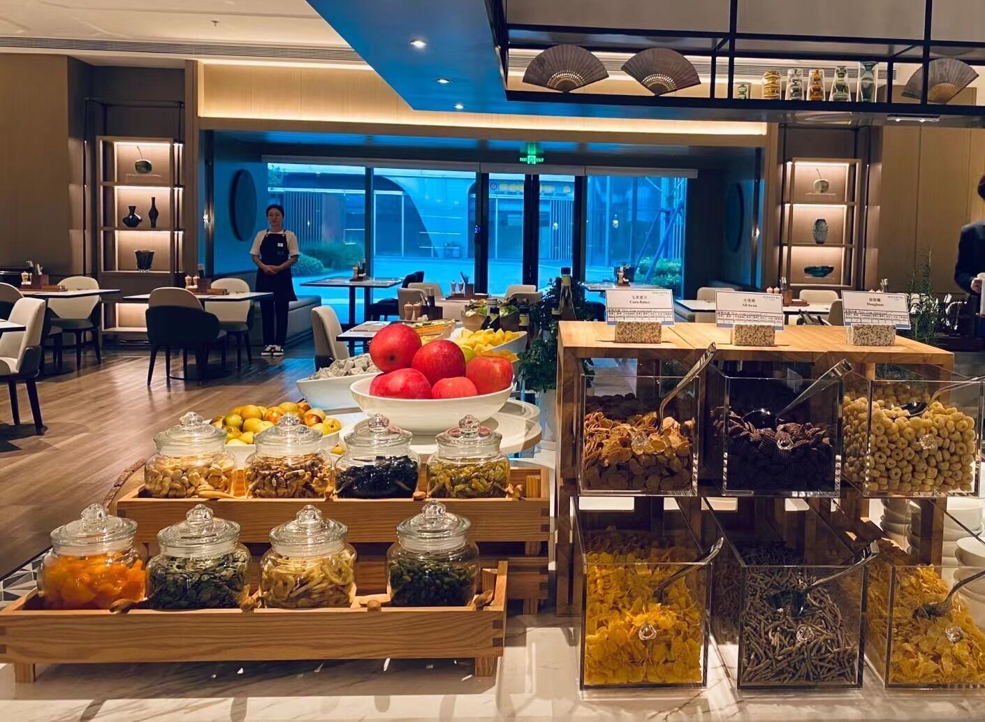 A buffet area with various food items and a seating area with tables and chairs.
