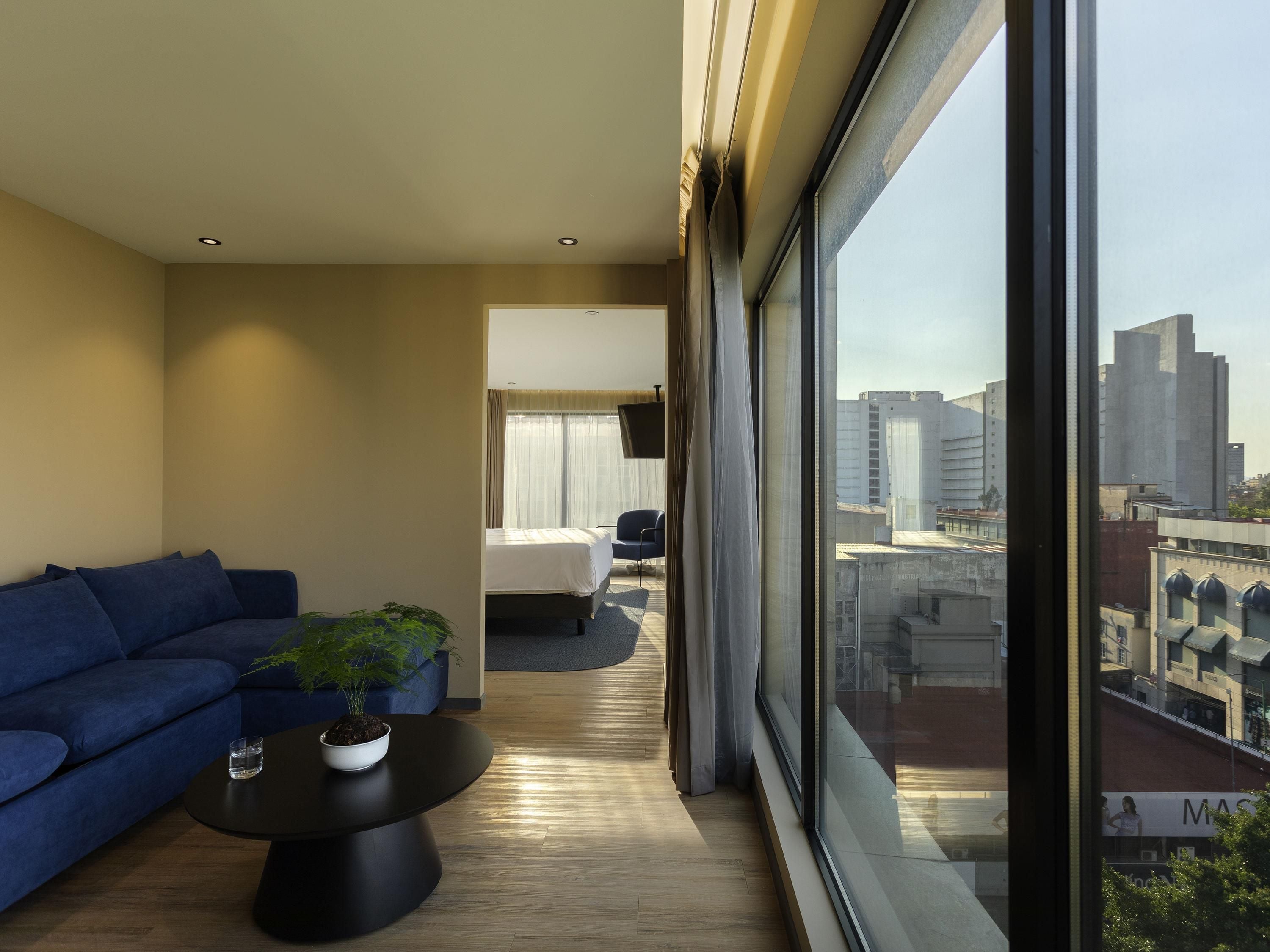 Une chambre d’hôtel moderne dotée d’une grande fenêtre, d’un canapé, d’une table basse et d’un lit.