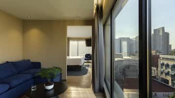Una habitación de hotel moderna con un ventanal grande, un sofá, una mesa de centro y una cama.