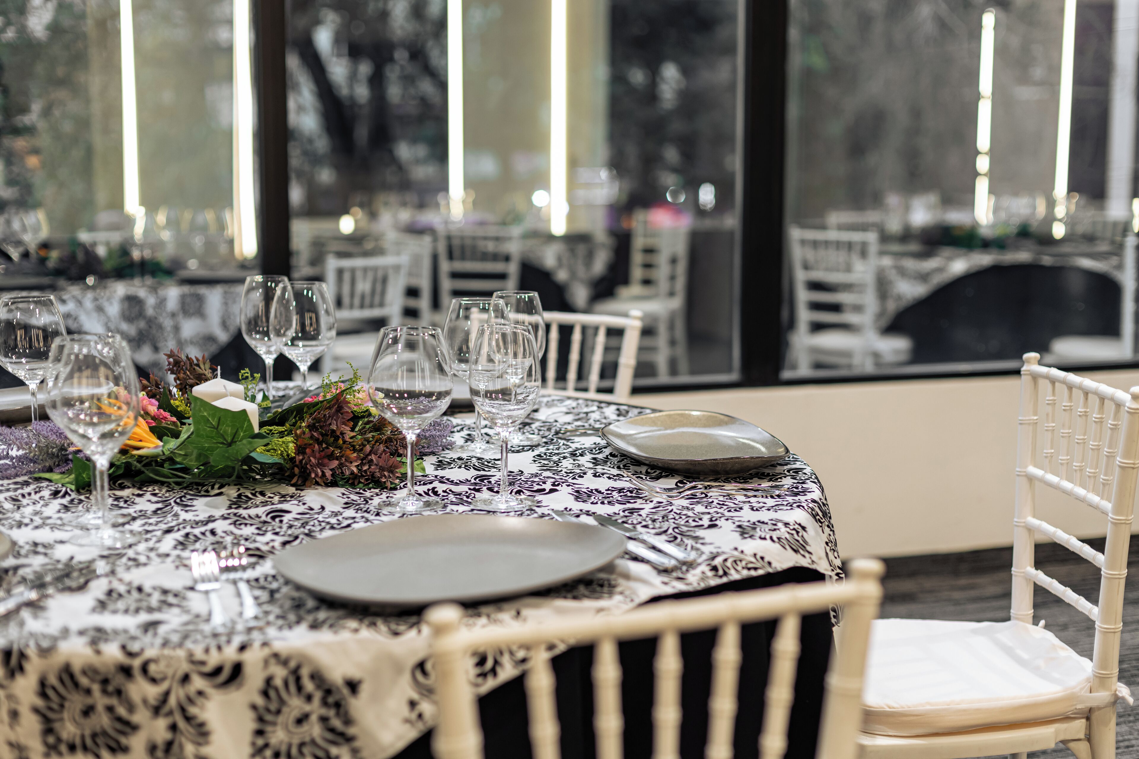 A dining table set with wine glasses, plates, and a centerpiece.