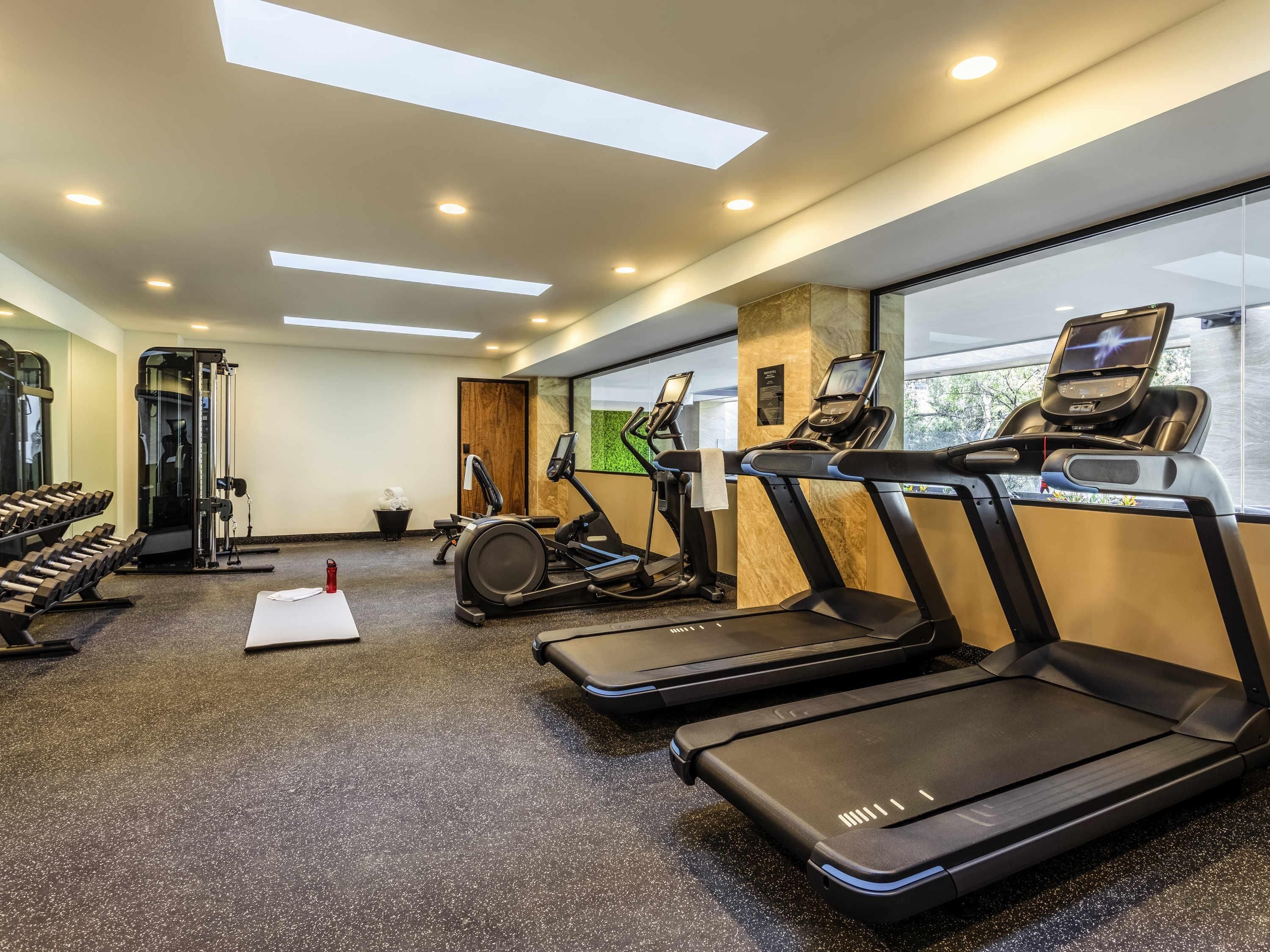 A gym with treadmills, a weight machine, and dumbbells.