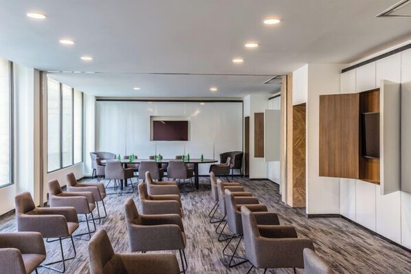 A conference room with a long table, multiple chairs, and a large screen. - Novotel México City Centro Histórico (Mexico City)