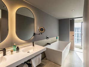 A modern bathroom with a large mirror, two sinks, a bathtub, and a view of a cityscape. - Novotel México City Centro Histórico (Mexico City)