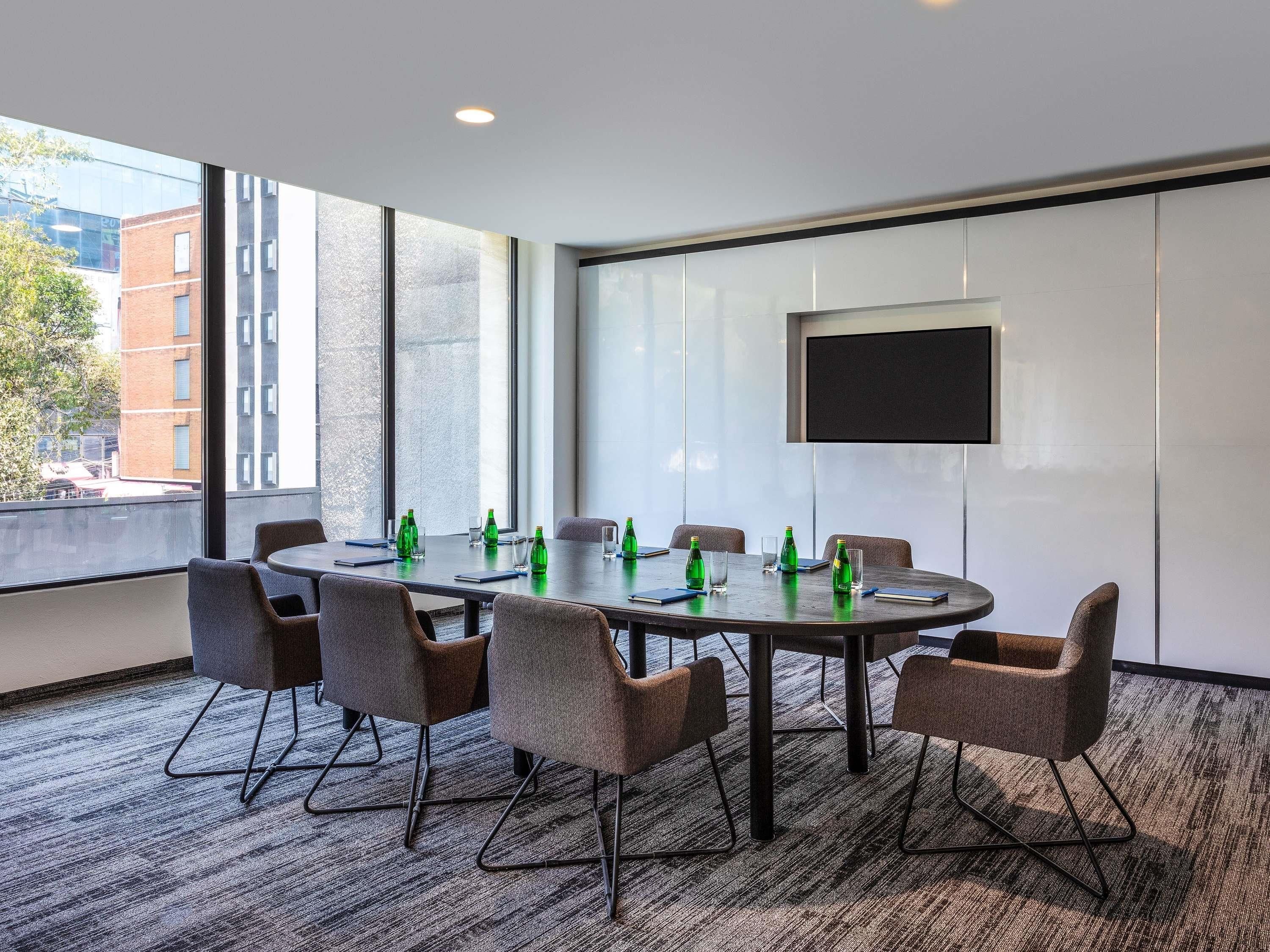 A conference room with a large table, chairs, a TV, and large windows.
