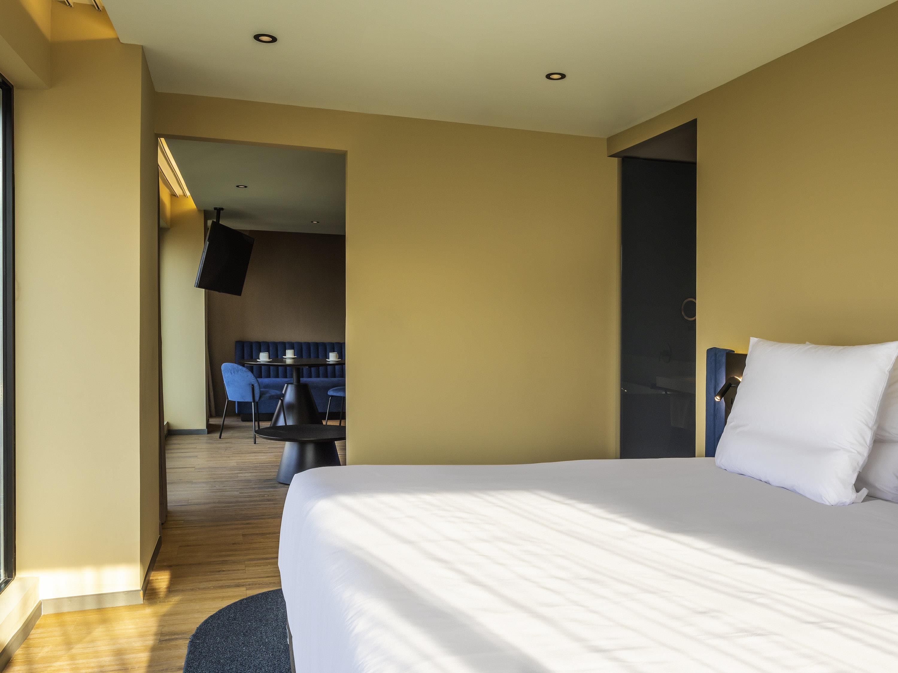 Una habitación de hotel con una cama grande, un área de descanso con una mesa y sillas, y una televisión.