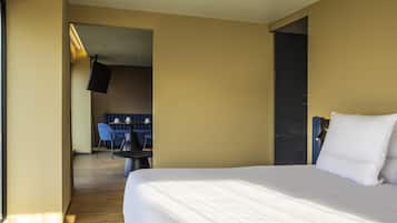 Una habitación de hotel con una cama grande, un área de descanso con una mesa y sillas, y una televisión.