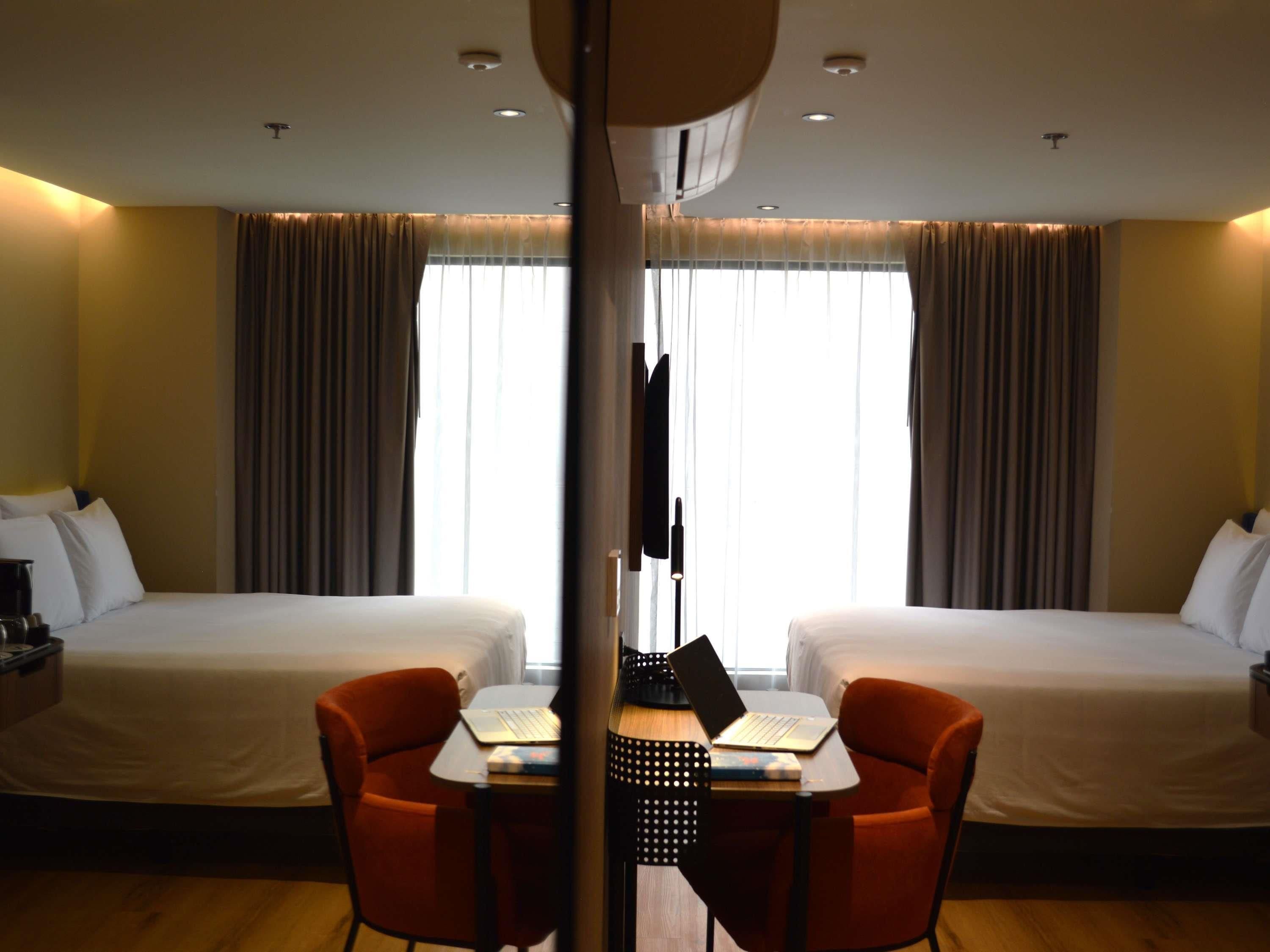 Habitación de hotel con dos camas, un escritorio con una computadora portátil y una silla.