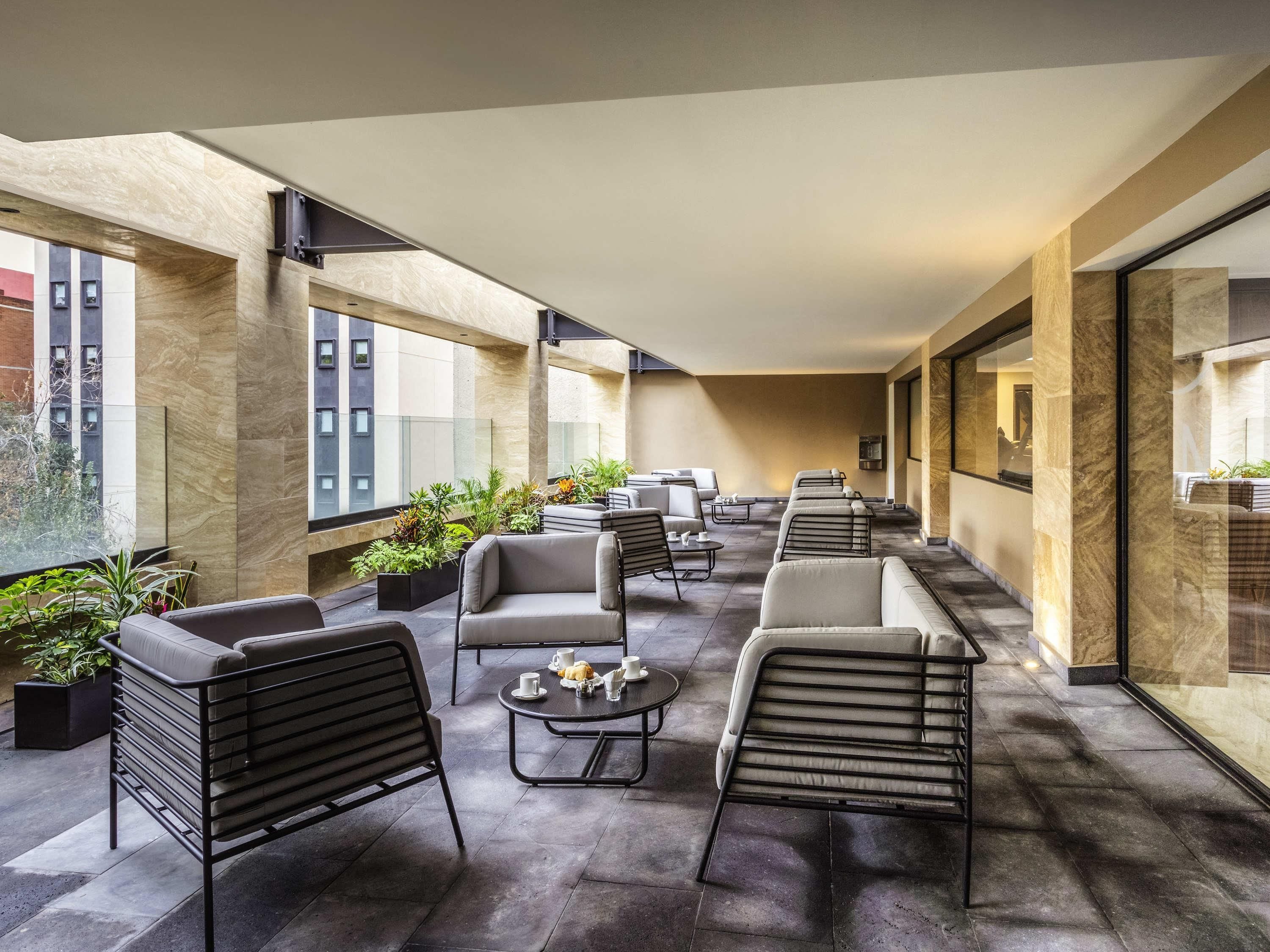 A modern lounge area with seating, tables, and potted plants.