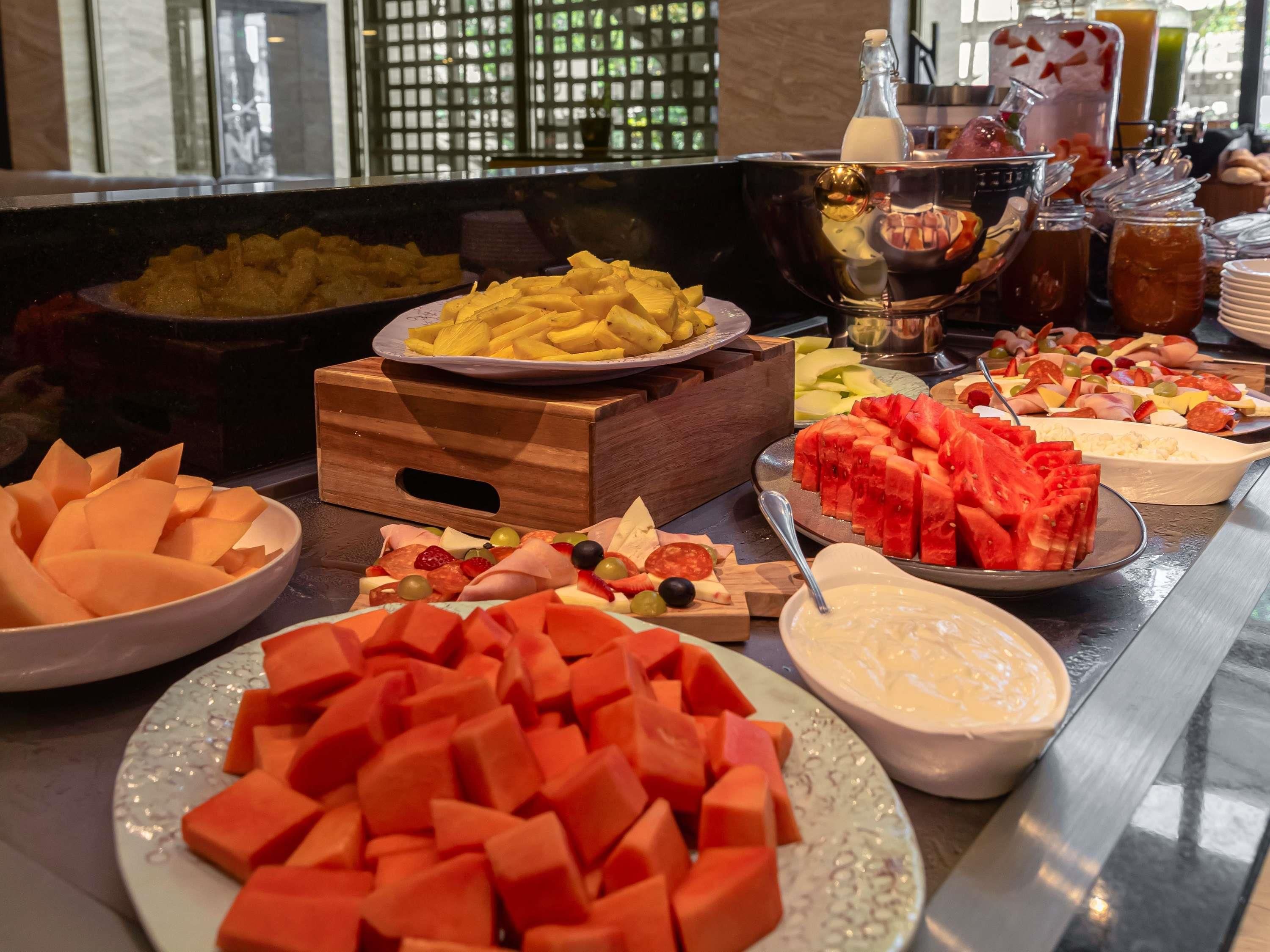 A buffet with various fruits, cheeses, and meats.