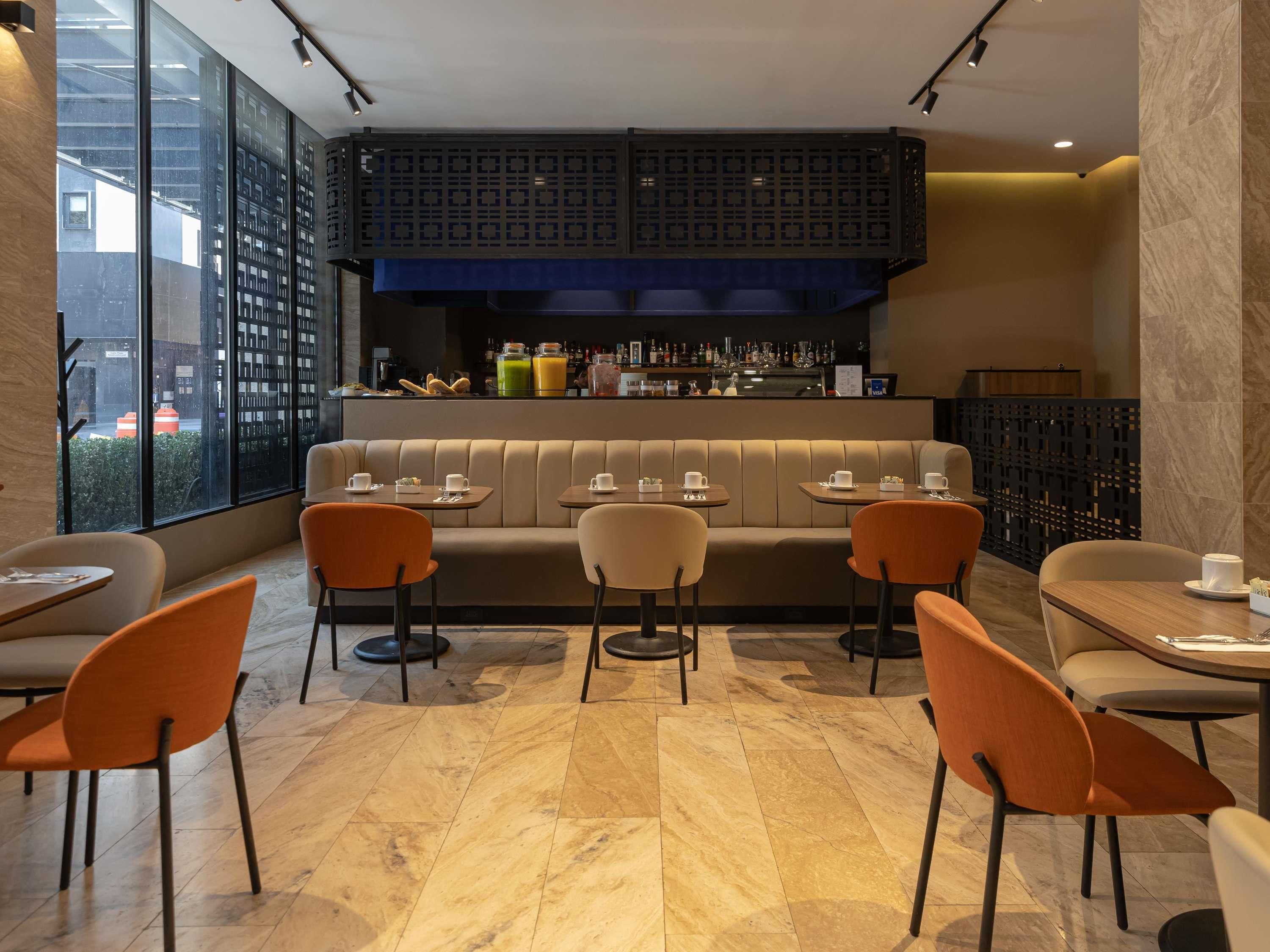 Ett modernt café med ett centralt placerat sittområde, en bar med ett varierat utbud av drycker och utsikt genom stora fönster.