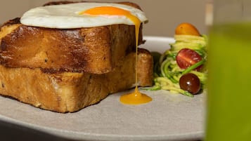 En tallrik med rostat bröd, ett stekt ägg och en liten sallad.