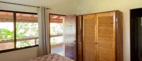 A bedroom with a bed, a ceiling fan, and a window with curtains.