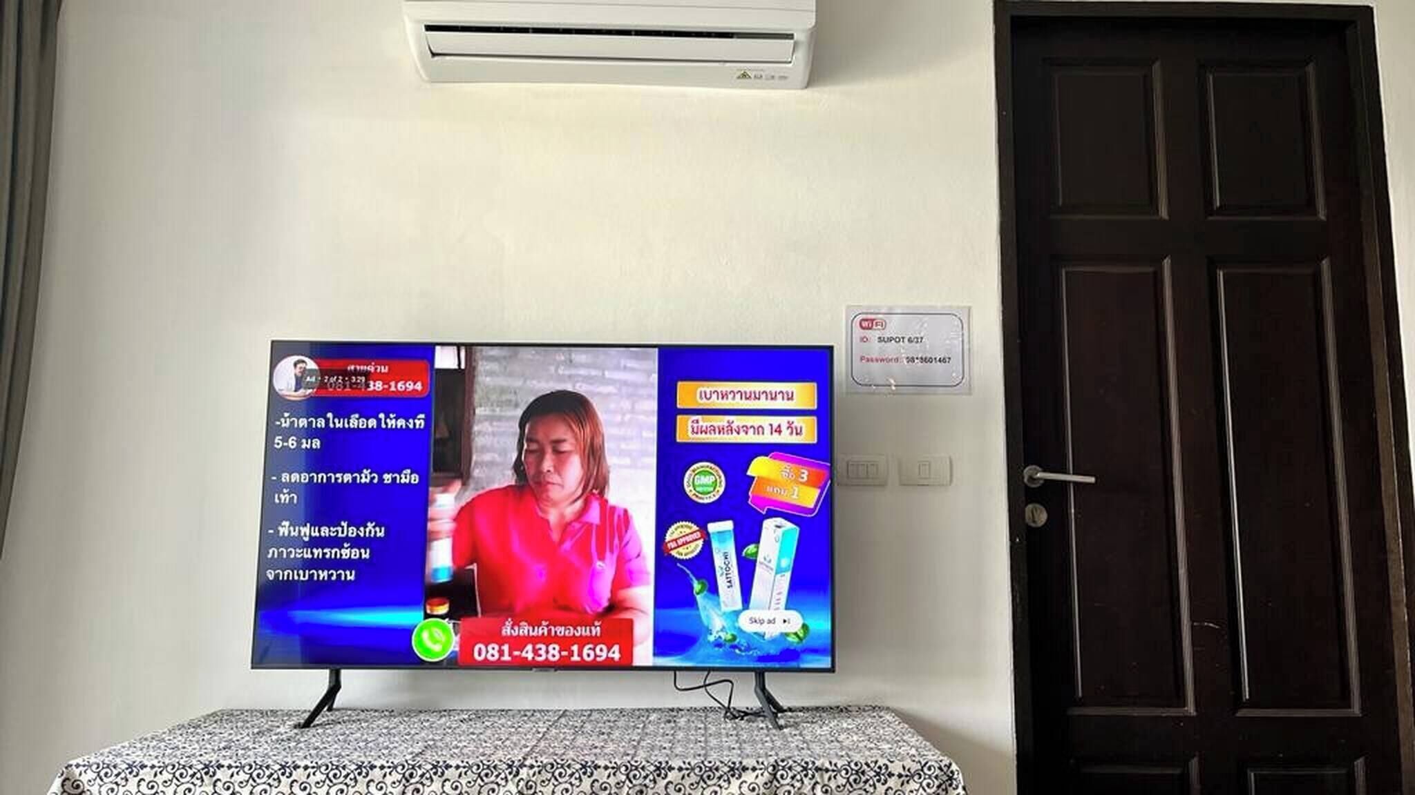 Un televisor montado en la pared que muestra un noticiero con un número de contacto visible.