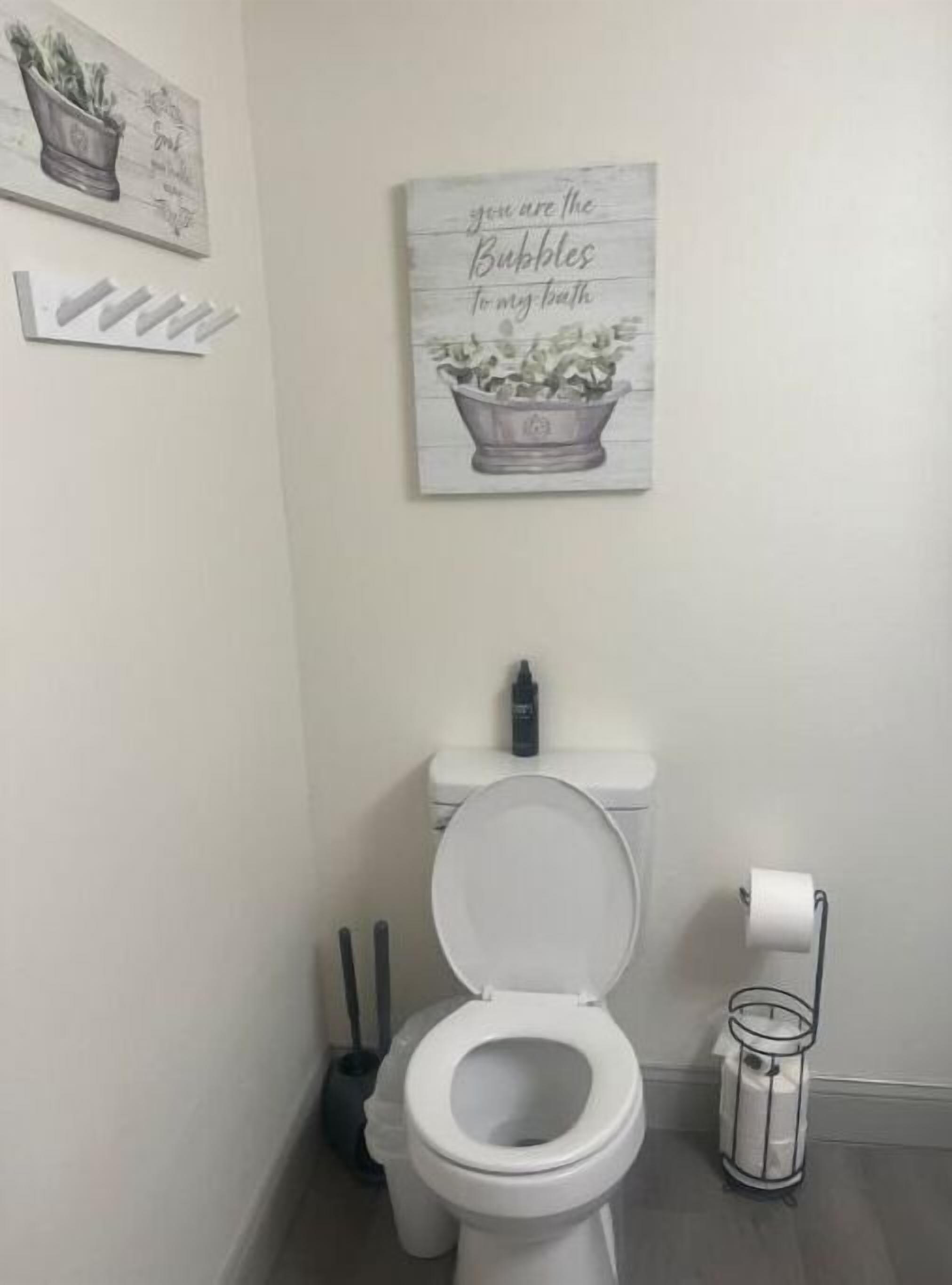 Ein Badezimmer mit Toilette, Mülleimer und einem an der Wand befestigten Toilettenpapierhalter.