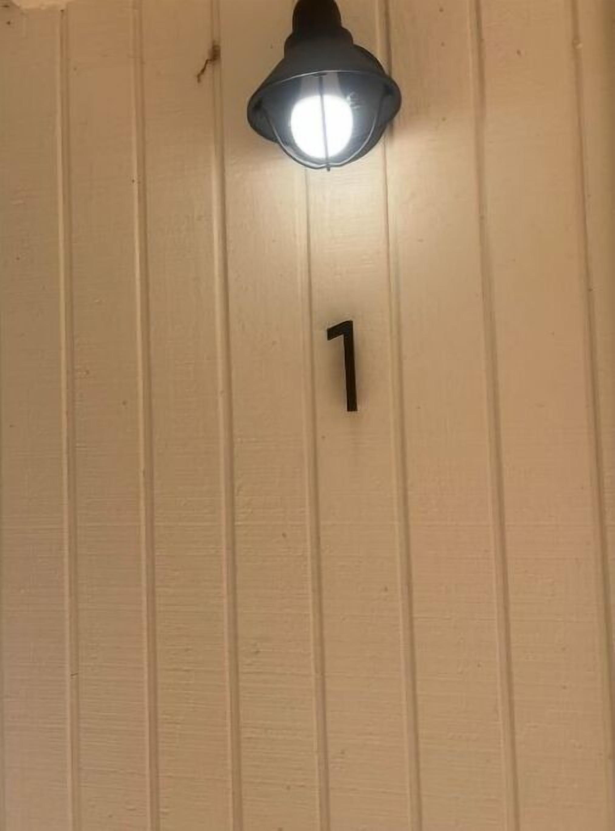 Un luminaire fixé au mur, au-dessus d’un mur de couleur beige, sur lequel figure un seul chiffre noir, le « 1 ».