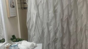 Een badkamer met een wit wastafel, een handdoek, een klein speelgoedfietsje en een douchegordijn.