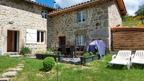 A stone house with a patio, outdoor seating, and a small garden.