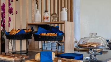 A breakfast buffet with bread, pastries, and condiments.