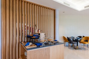 A modern dining area with a wooden partition, a counter with bread and pastries, and a table with chairs. - Brit Hotel Privilège Paris - Rosny (Rosny-sous-Bois)