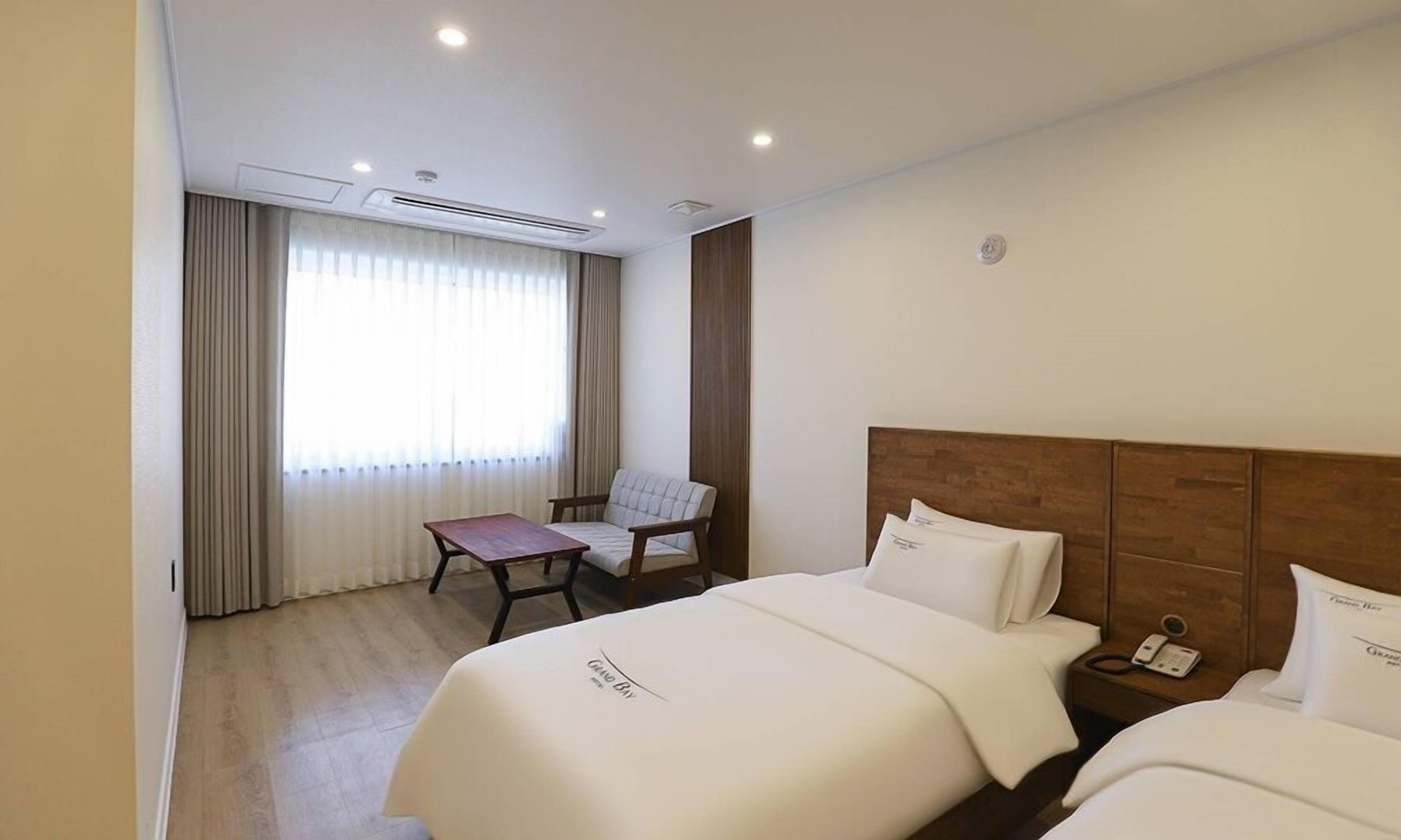 A hotel room with two beds, a desk, and a chair.