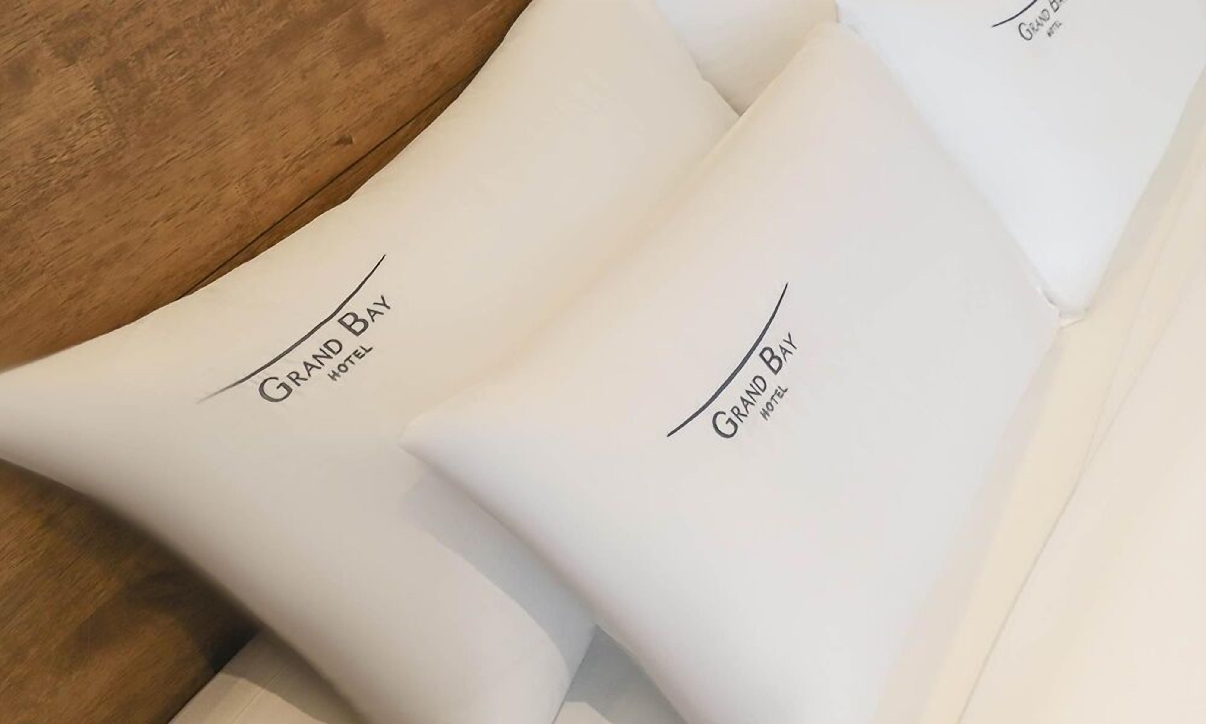 Folded white towels with "Grand Bay Hotel" printed on them.