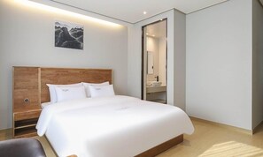 A modern hotel room with a large bed, wooden headboard, and a painting on the wall. - Hotel Grand Bay Boryeong (Boryeong)