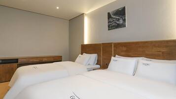 Habitación de hotel con dos camas, cabecero de madera, mesita de noche y un cuadro enmarcado en la pared.