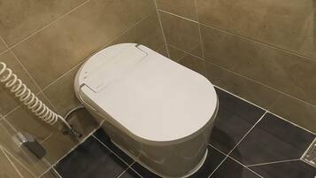 Un moderno WC con pedale, getto bidet e porta carta igienica.