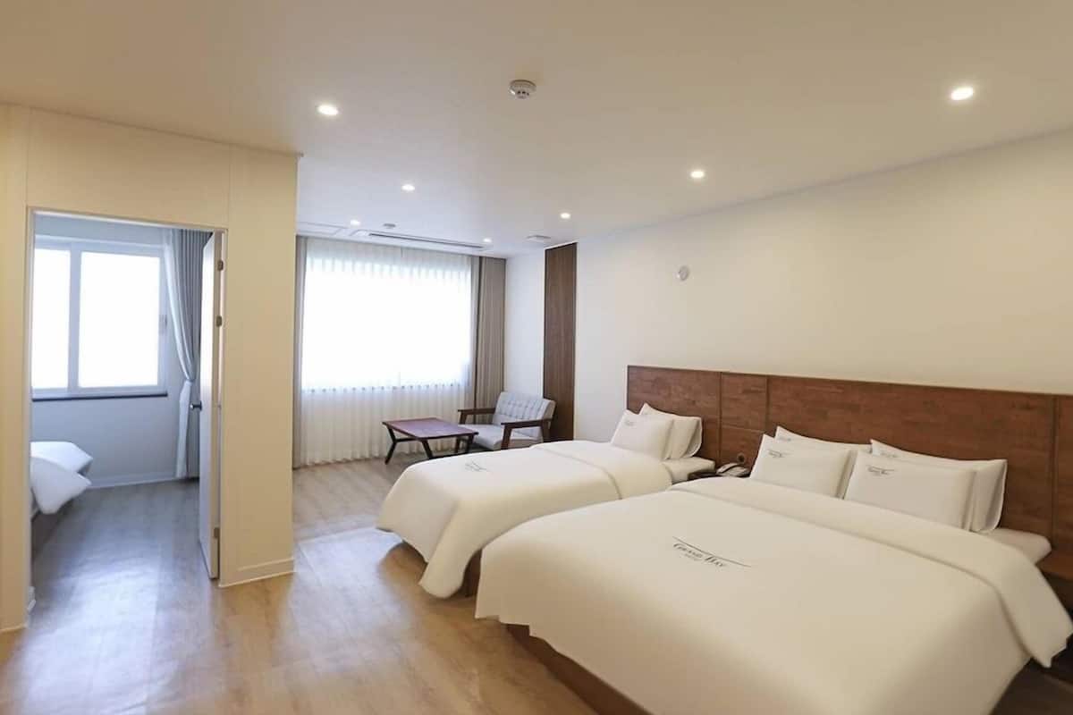 A hotel room with two beds, a desk, and a chair.