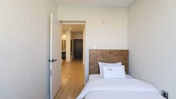 A hotel room with a wooden headboard, a bed with white bedding, and a door leading to a hallway.