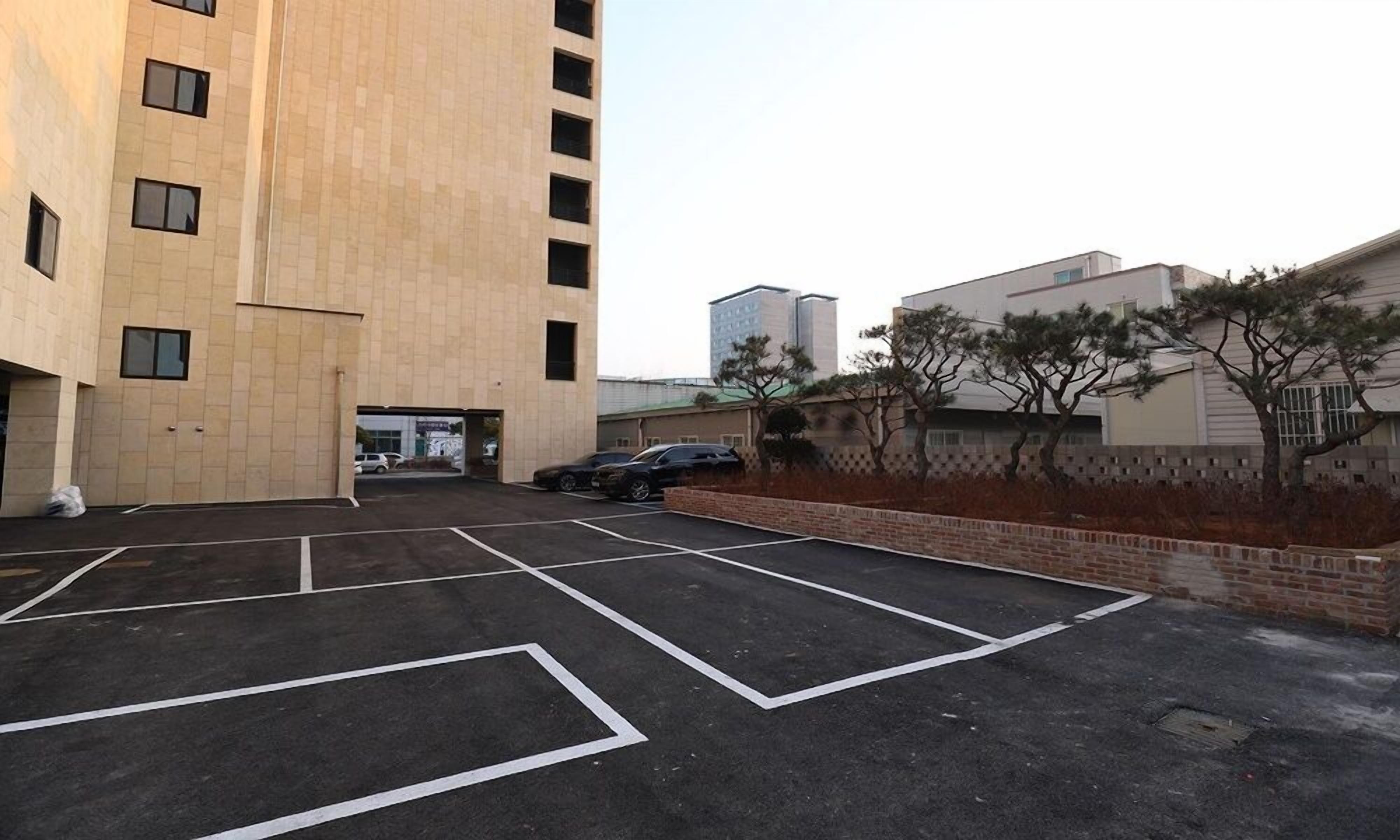 A parking lot with marked spaces and a building with multiple floors and windows.
