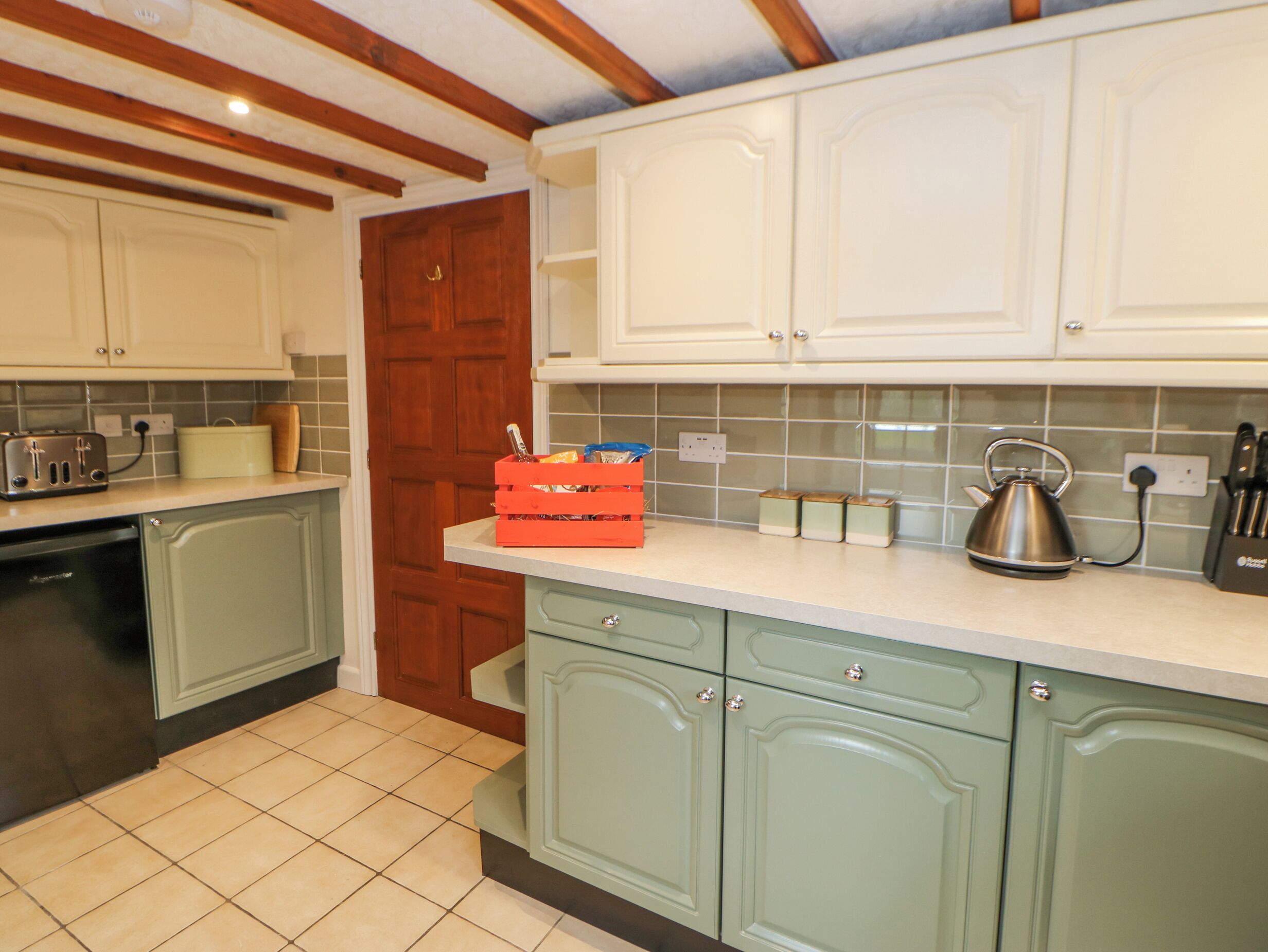 A kitchen with green cabinets, a wooden ceiling, and a tiled backsplash.