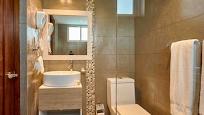Et moderne badeværelse med en rund vask, toilet og en brusekabine i glas.