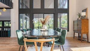 A dining area with a round table, green upholstered chairs, and a white furry rug.