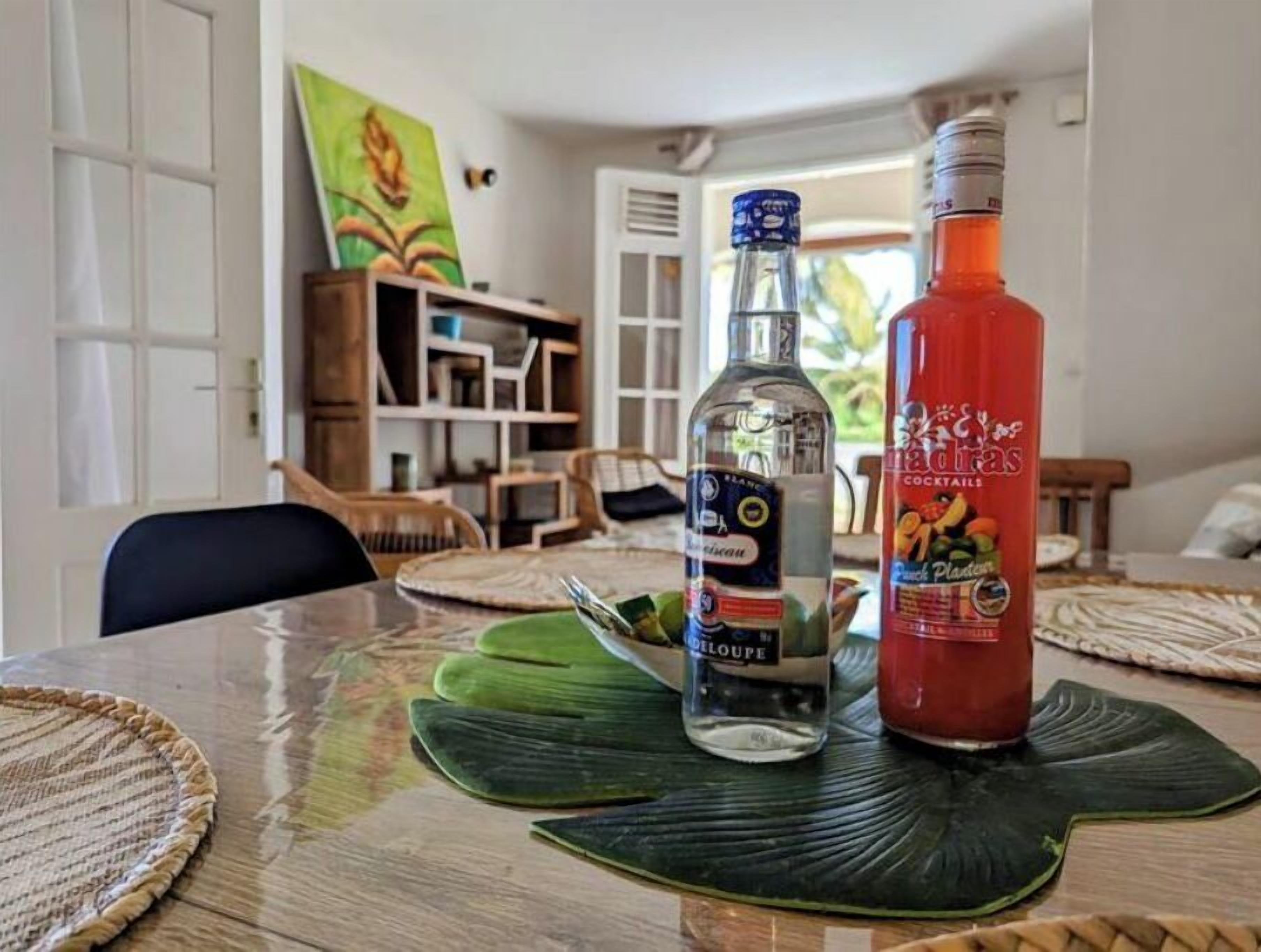 Una mesa de comedor con una botella de Delmotte y una botella de salsa cóctel.