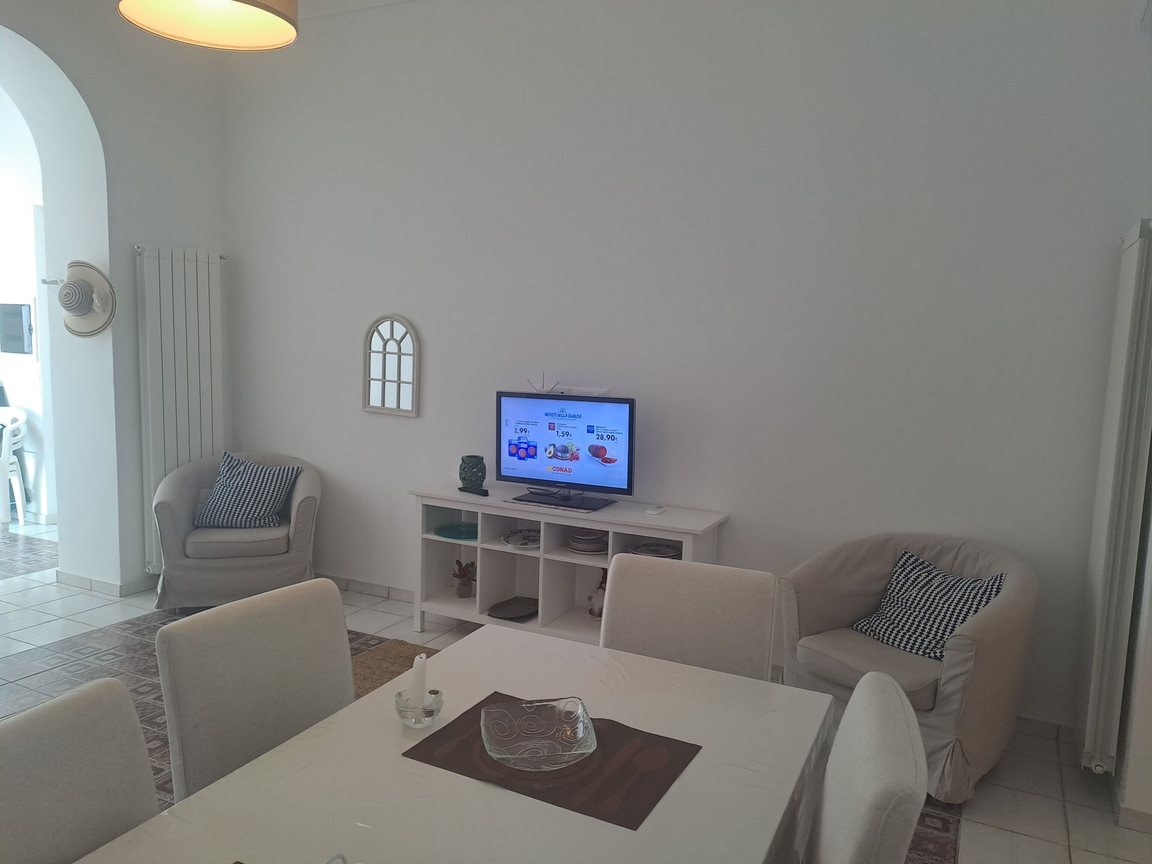 A living room with a dining table, two sofas, a TV, and a window.