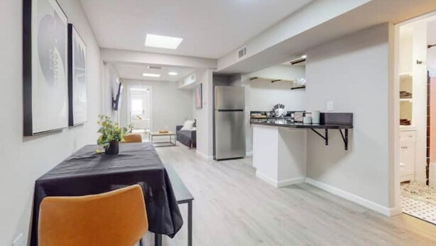 A modern kitchen with a built-in refrigerator, a dining area with a table and chairs, and a hallway leading to a living space. - ⟫Dog Run & Courtyard 2 Bedroom Apt w/King Bed W&D (Albuquerque)