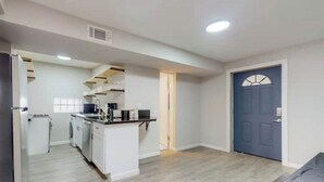A compact kitchen with white cabinets, a black countertop, and a blue door. - ⟫Dog Run & Courtyard 2 Bedroom Apt w/King Bed W&D (Albuquerque)