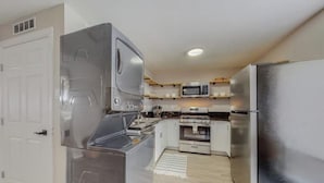 A compact kitchen with stainless steel appliances, a microwave, oven, and refrigerator.
