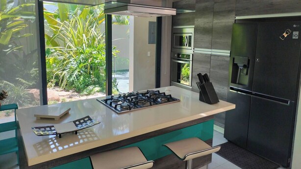 Una cocina moderna con una isla central, electrodomésticos de acero inoxidable y vistas al exterior.