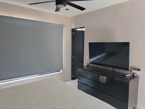 A bedroom with a large bed, a TV on a dresser, a ceiling fan, and a sliding door. - Elegant big House Nvo Vta (Nuevo Nayarit)