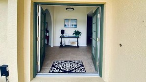 A hallway with a black and white patterned rug, a painting on the wall, and a potted plant. - Villa Gone Golfing (Rotonda West)