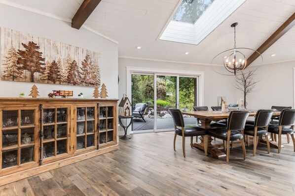 A dining area with a wooden cabinet, a chandelier, and a view of the outdoors.